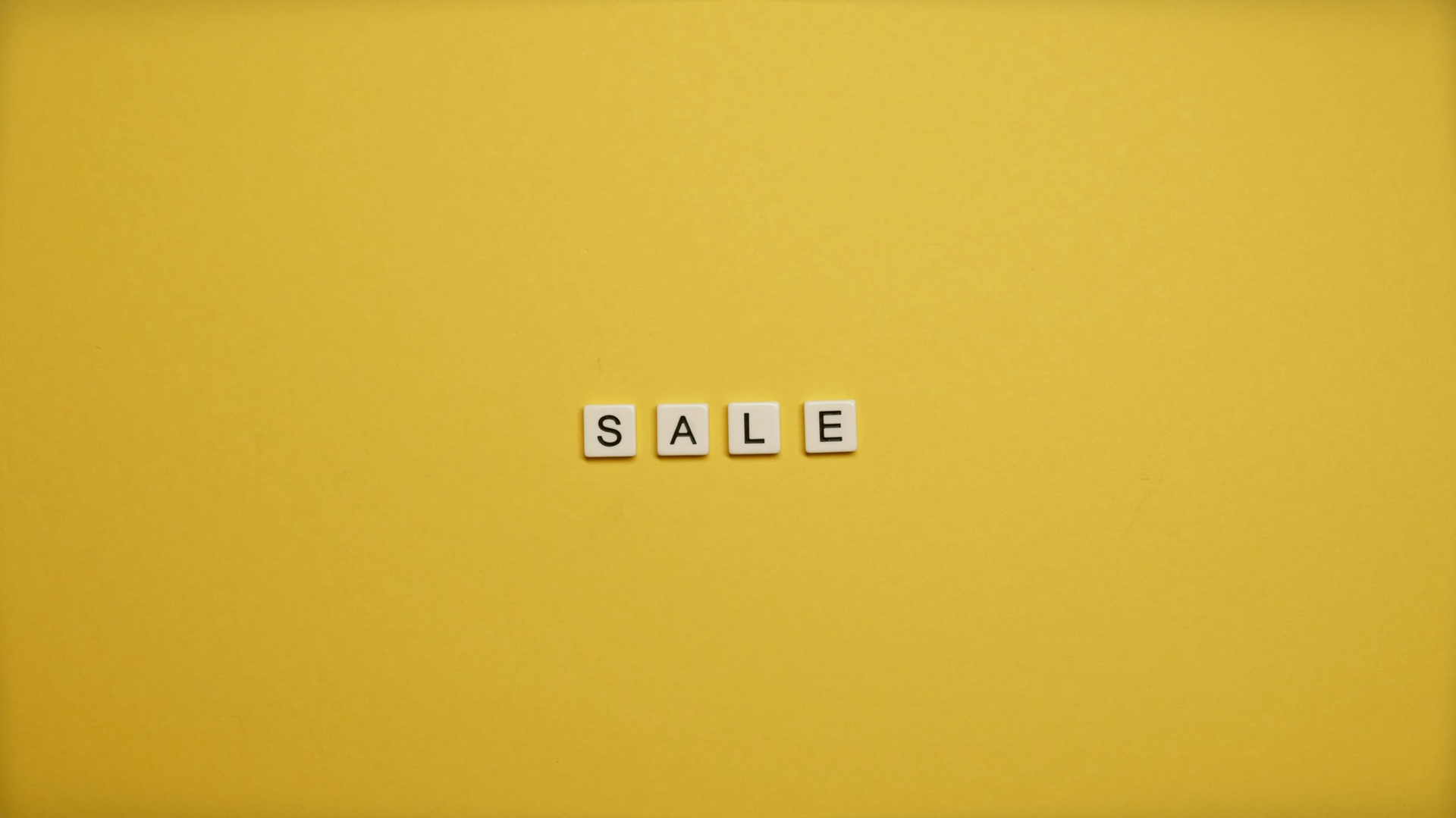 SALE spelled with letter tiles on a yellow background