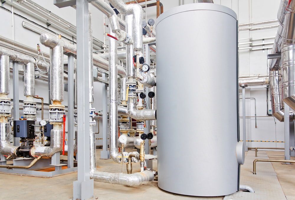 A Large Gray Tank Is Sitting In The Middle Of A Factory Filled With Pipes — Justin Drew Plumbing in Grovedale, VIC