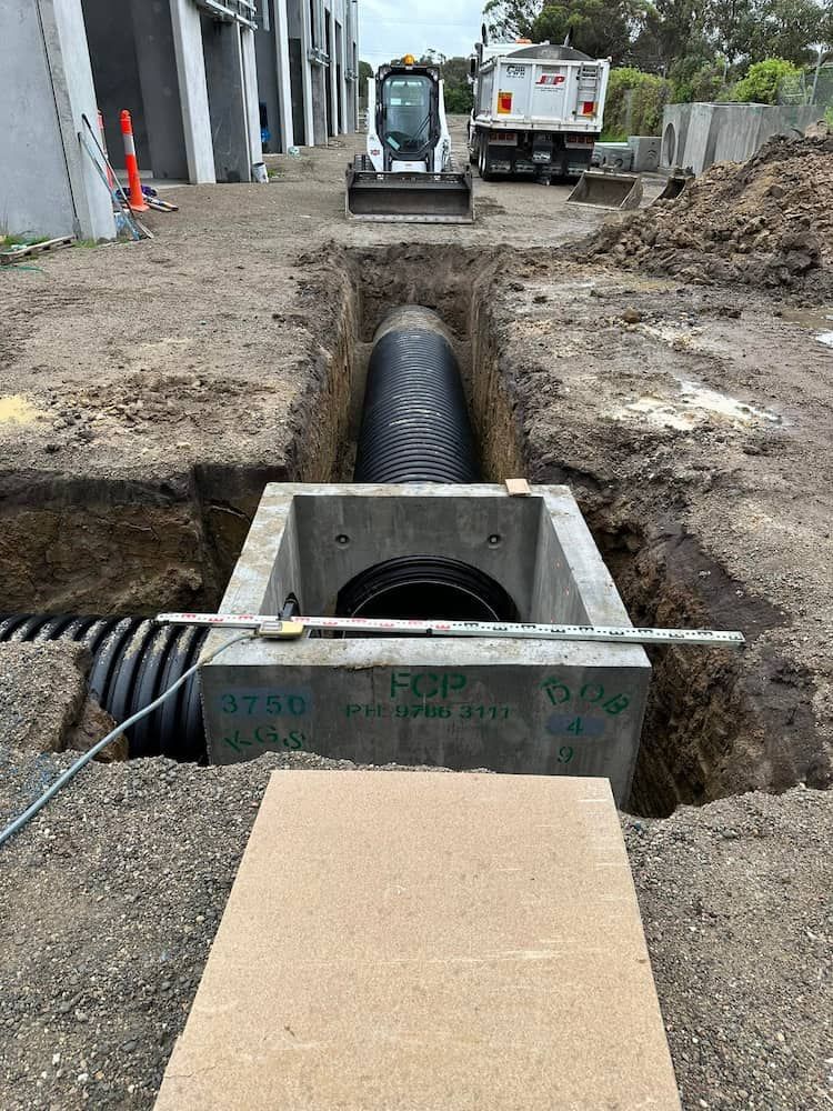 A Large Pipe Is Being Installed In A Hole In The Ground — Justin Drew Plumbing in Grovedale, VIC