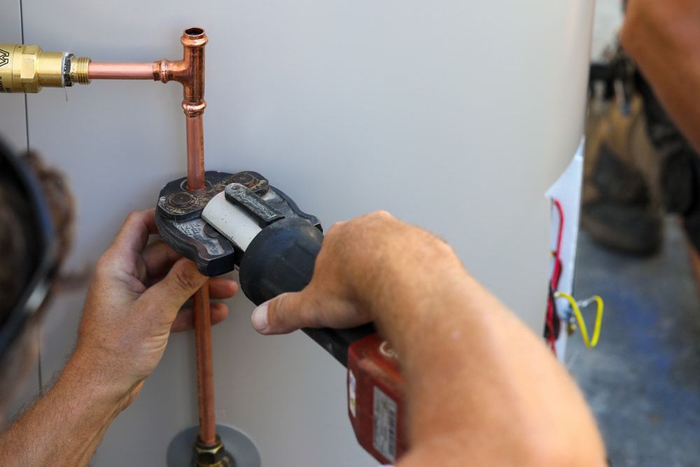 A Man Is Working On A Copper Pipe With A Wrench — Justin Drew Plumbing in Newtown, VIC