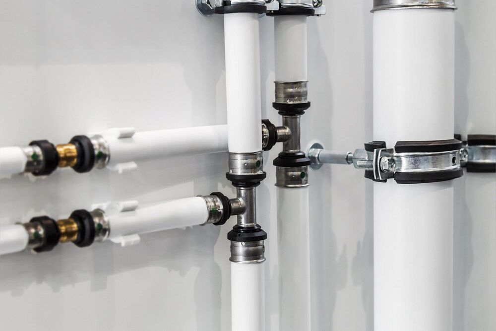 A Row Of White Pipes Attached To A Wall — Justin Drew Plumbing in Highton, VIC