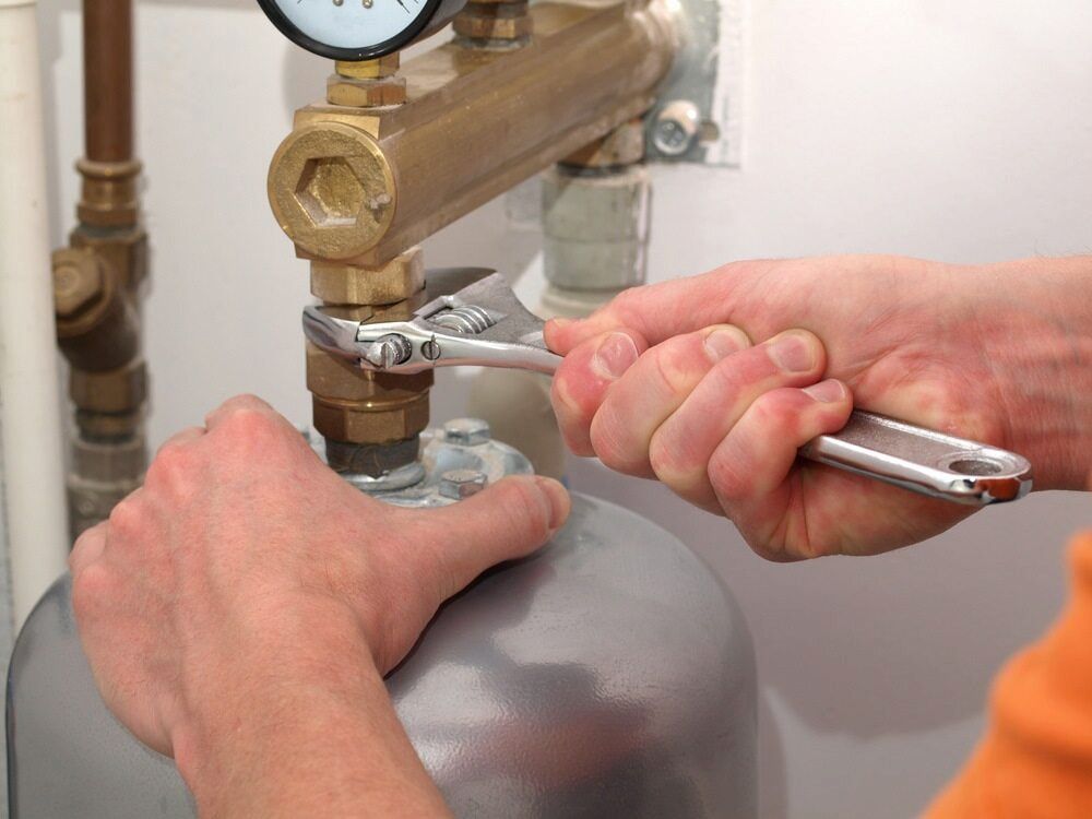 A Person Is Working On A Pipe With A Wrench — Justin Drew Plumbing in Grovedale, VIC