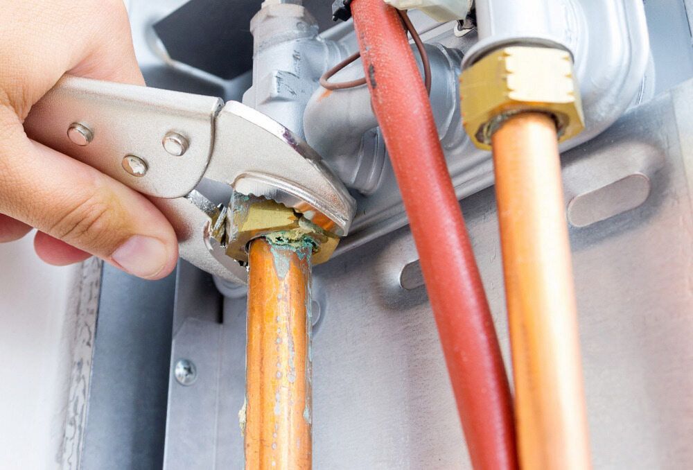A Person Is Fixing A Copper Pipe With A Wrench — Justin Drew Plumbing in Grovedale, VIC
