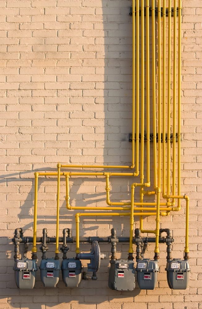 A Row Of Gas Meters On A Brick Wall — Justin Drew Plumbing in Grovedale, VIC