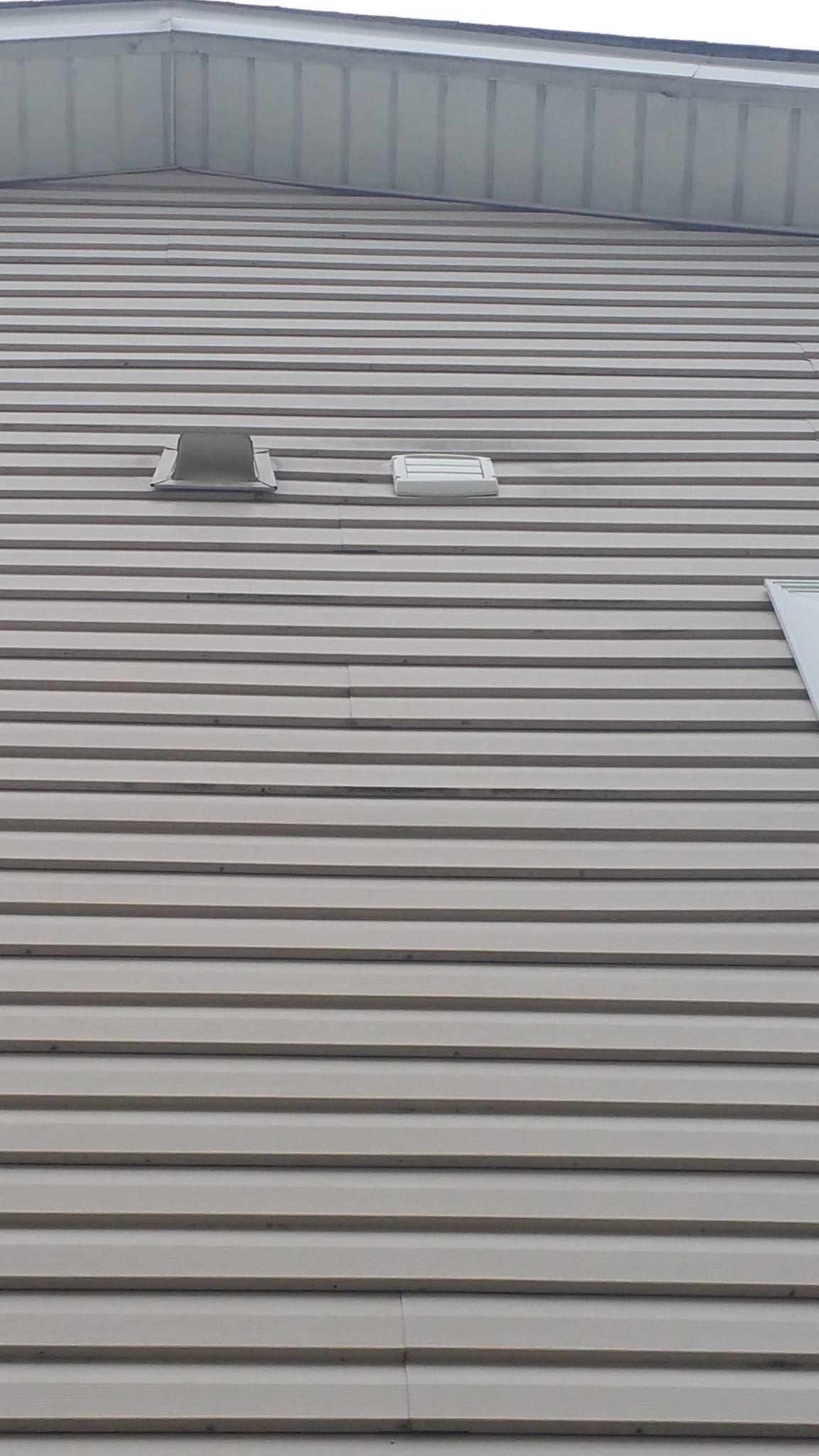 Tan, horizontally-lined siding on a building with two rectangular vents.
