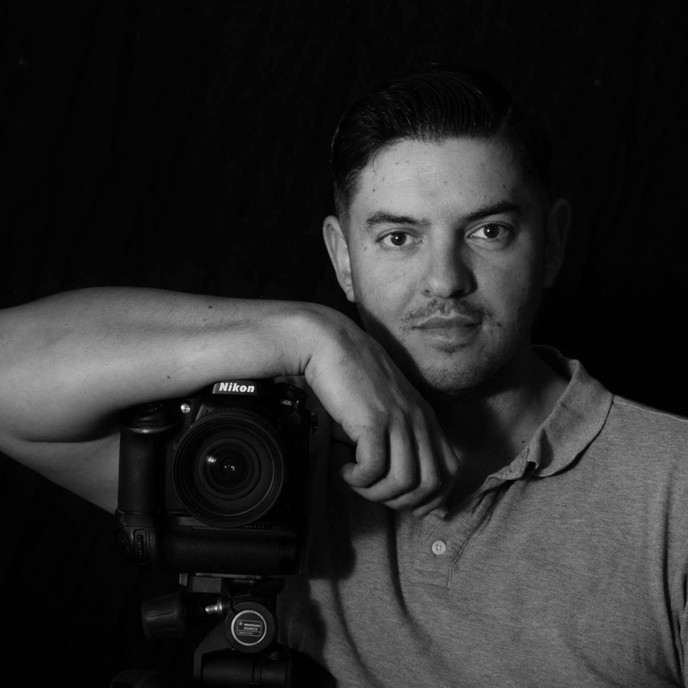A man is holding a camera in a black and white photo.