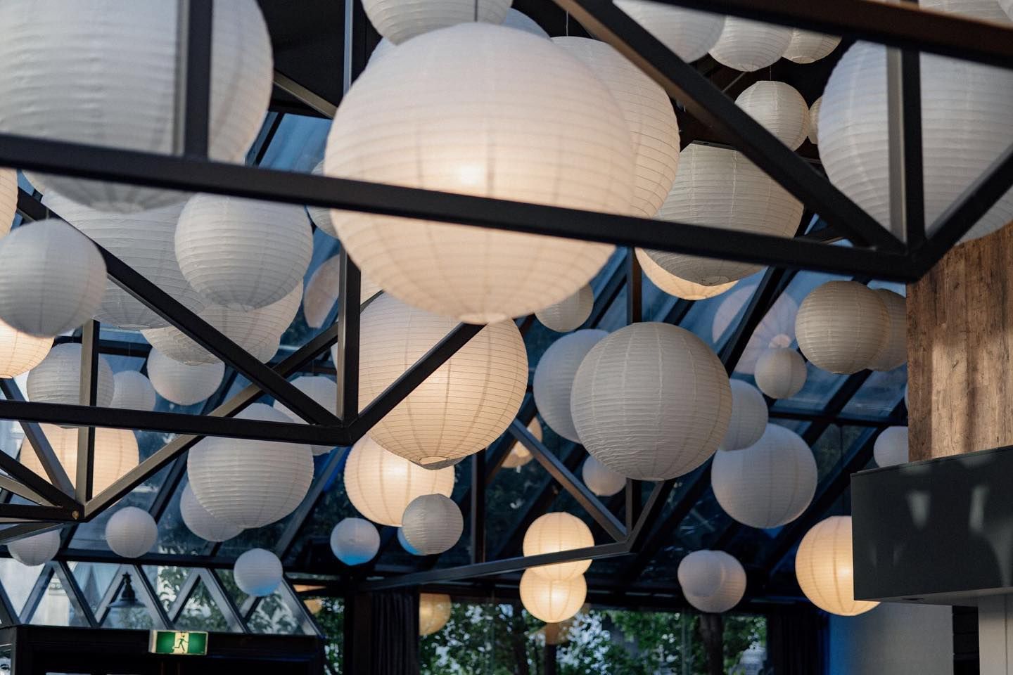 A bunch of white paper lanterns are hanging from the ceiling