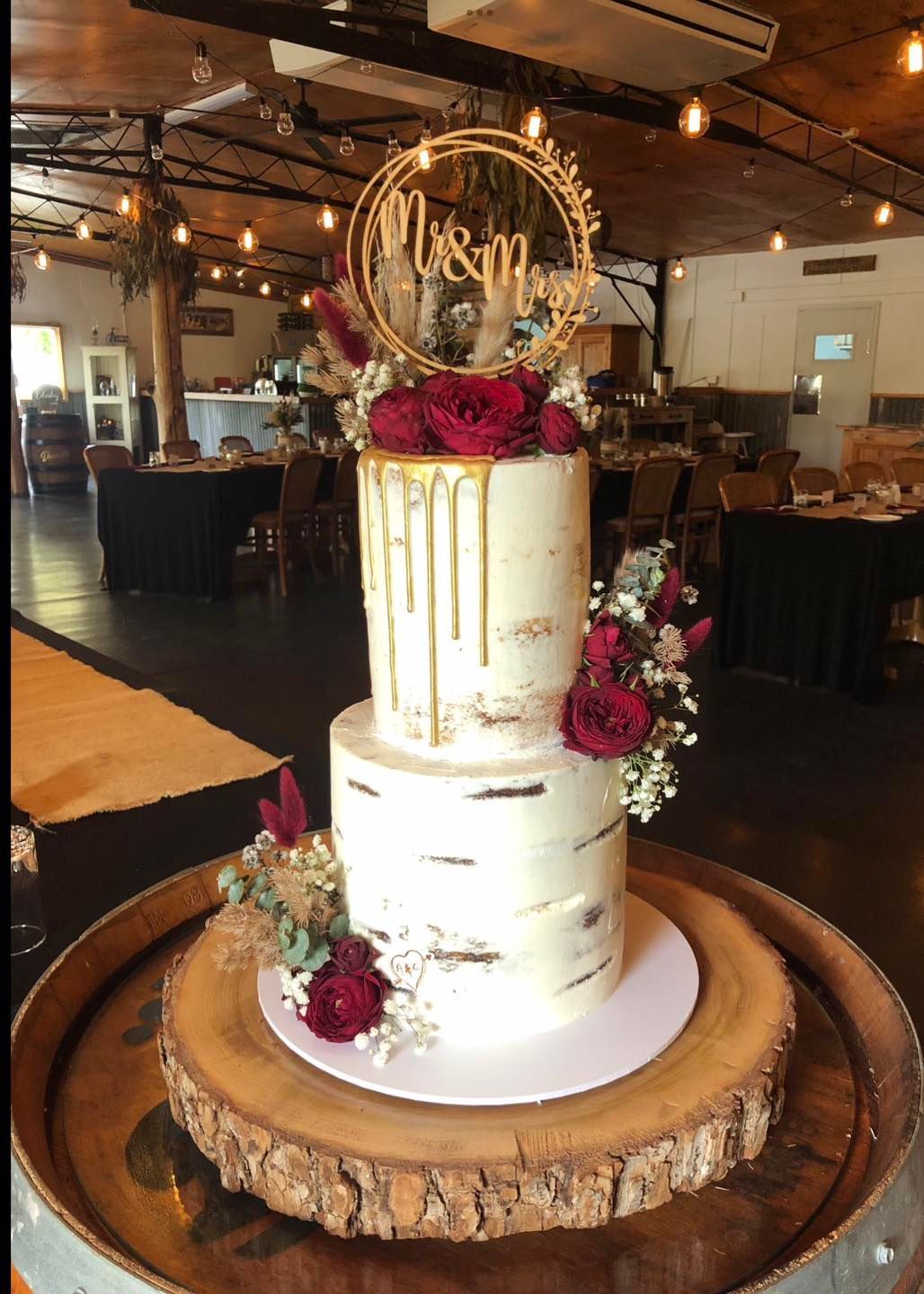 A wedding cake is sitting on top of a wooden barrel.