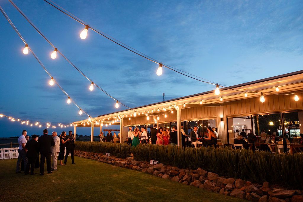 A group of people are standing under a covered area with lights hanging from the ceiling.