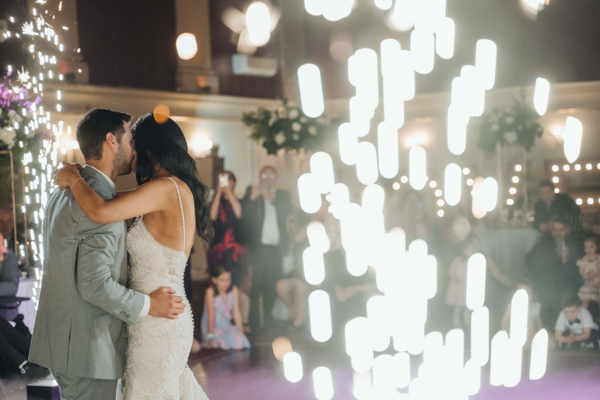 A bride and groom are kissing on the dance floor at their wedding reception.