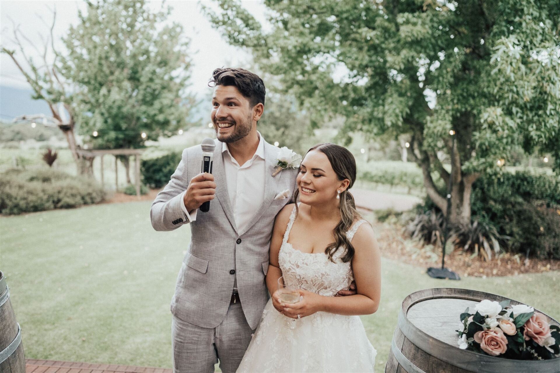 A bride and groom are standing next to each other holding a microphone.