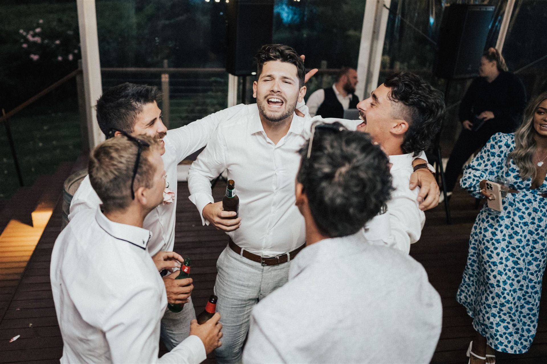 A group of men are dancing together at a wedding reception.