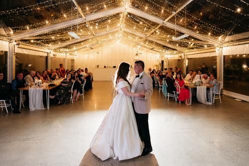 A bride and groom are dancing in front of a crowd at their wedding reception.