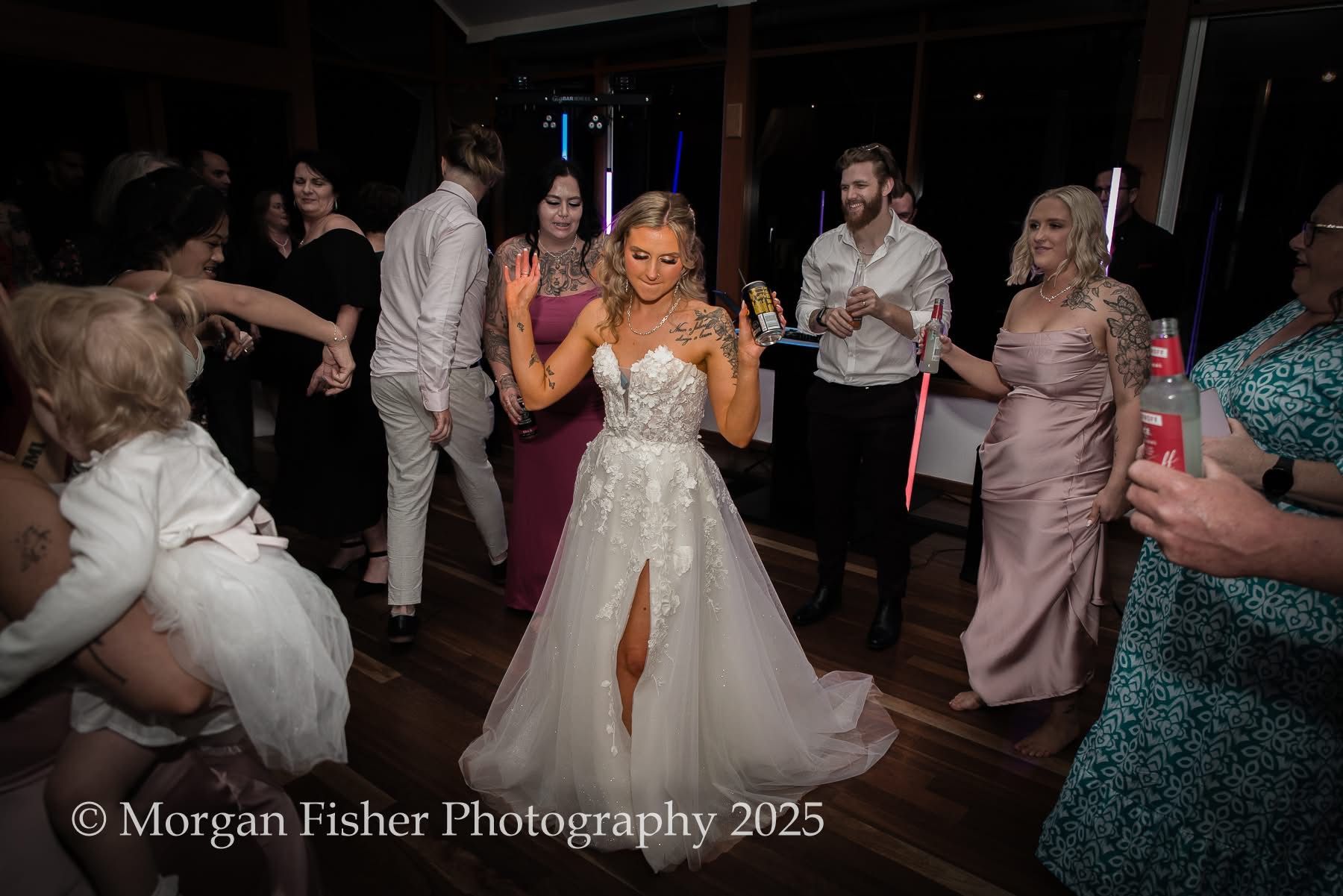A bride in a wedding dress is dancing with her wedding party.