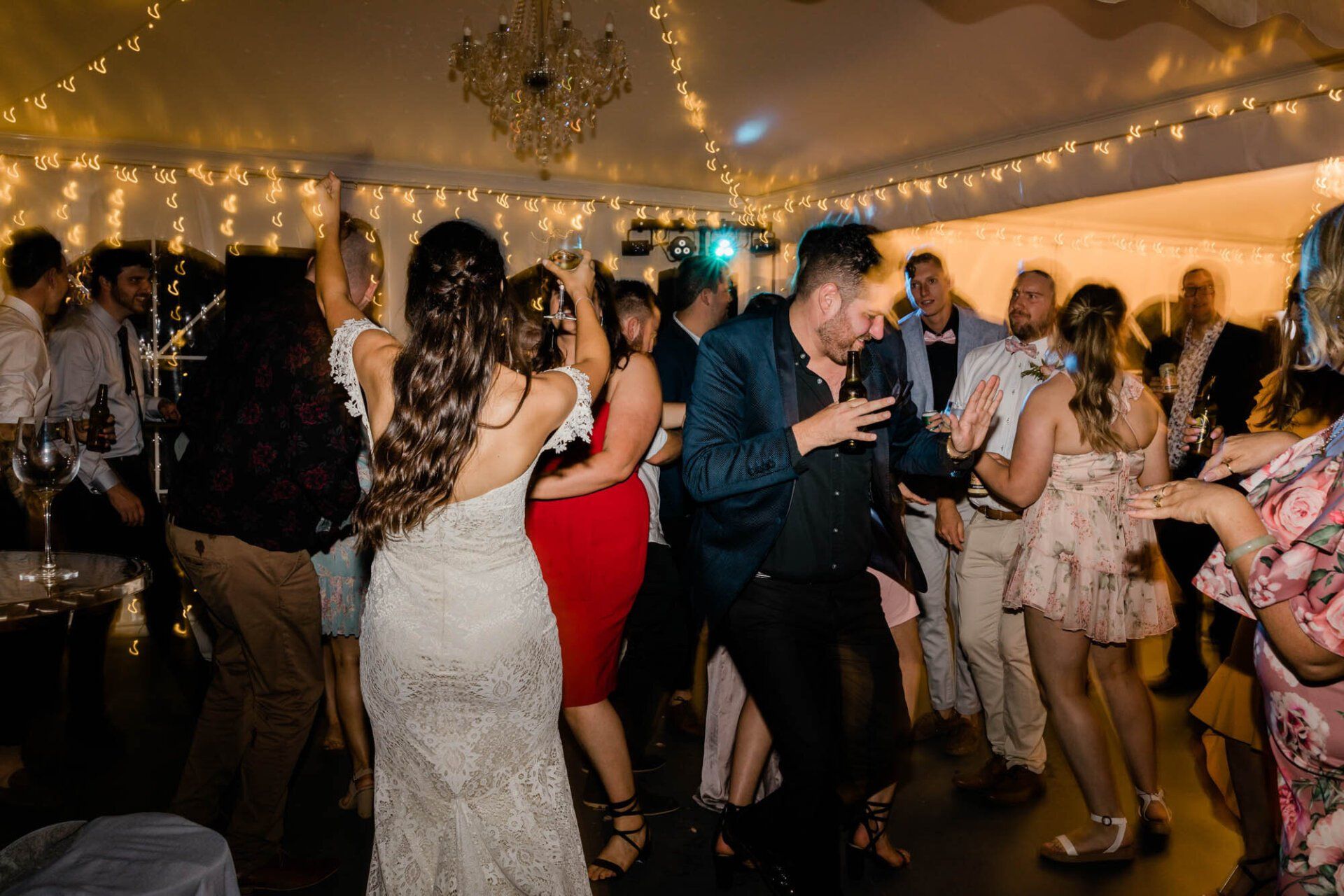 A group of people are dancing at a wedding reception.