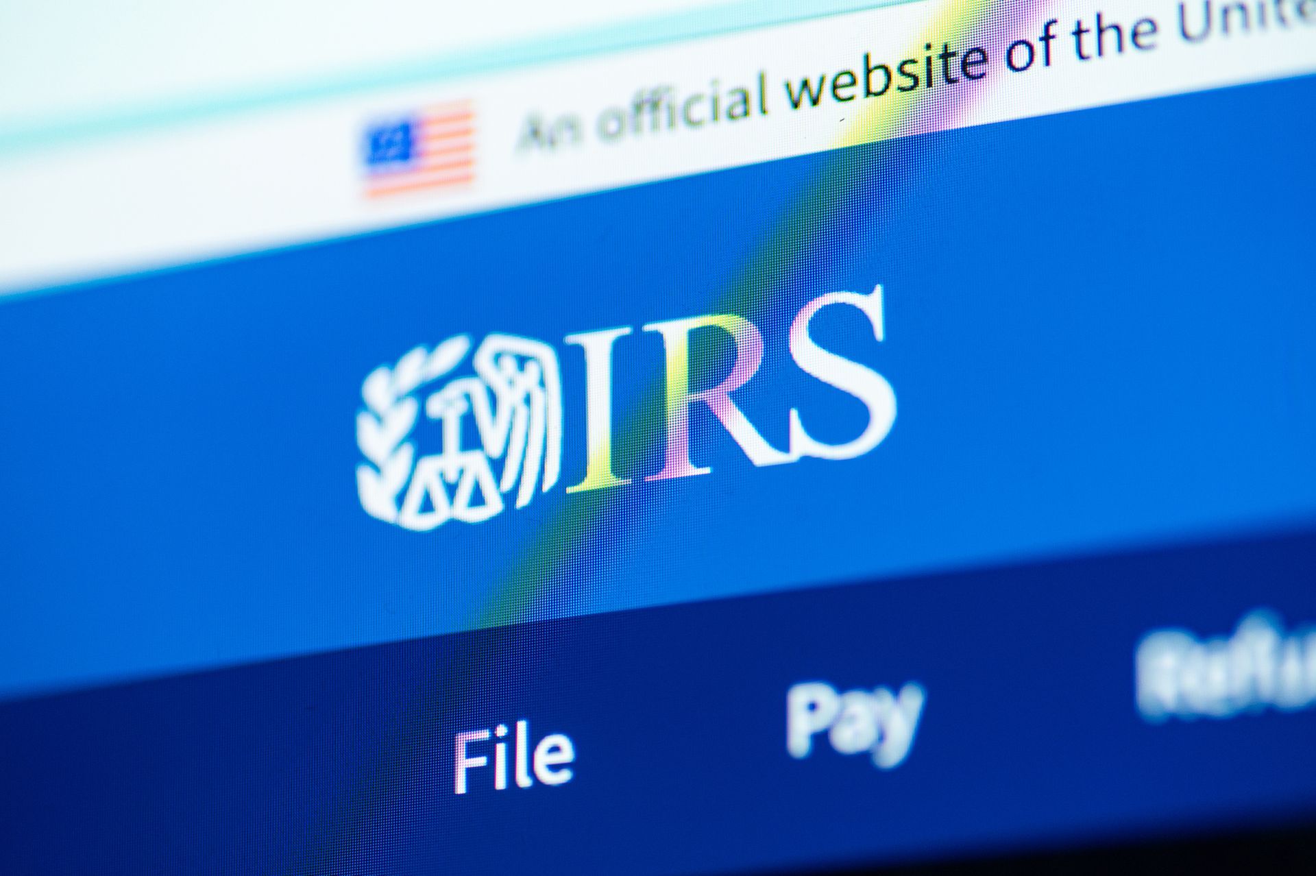 Person using a calculator, surrounded by paperwork, likely working on taxes.