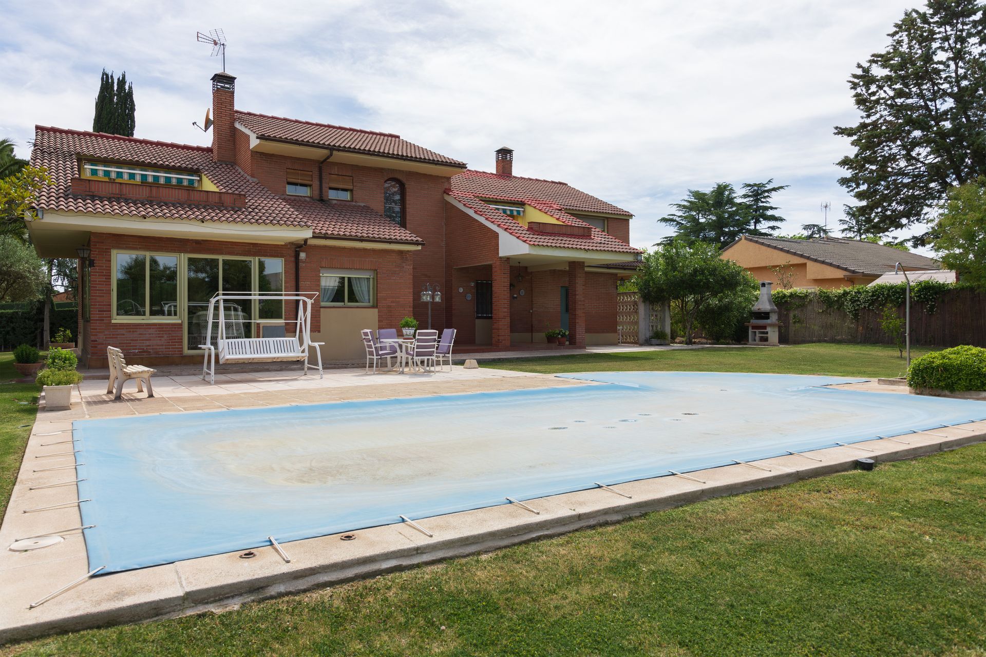 Brick house with covered swimming pool in a landscaped backyard.