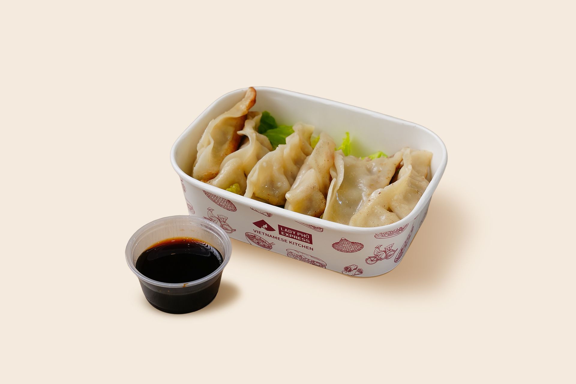 Takeout box of dumplings with a small cup of soy sauce on a light background