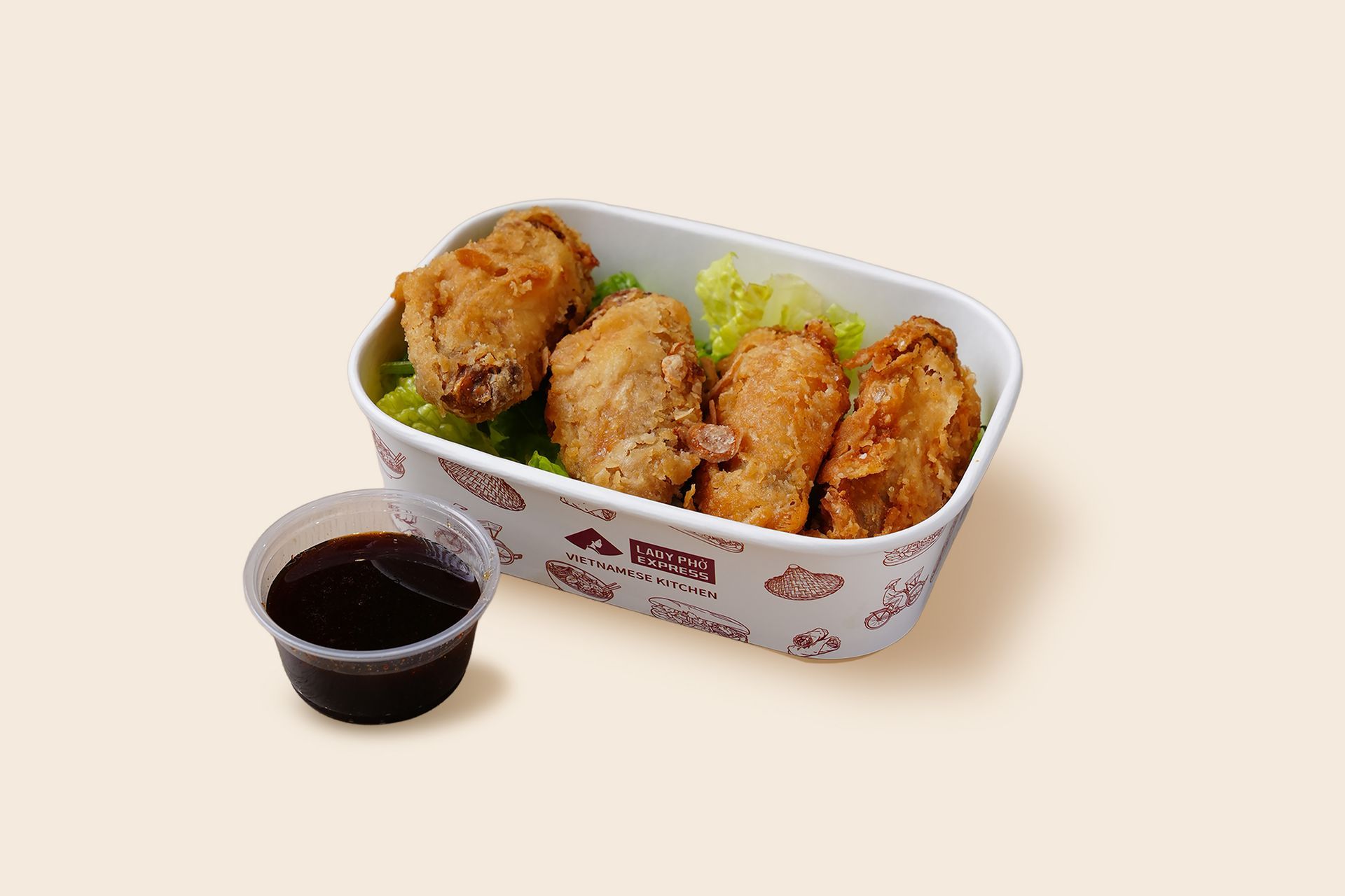Fried chicken pieces in a white tray with a cup of dark dipping sauce on a beige background