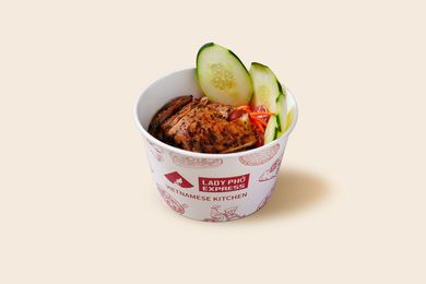 Paper cup of roasted chicken salad topped with cucumber slices on a light background