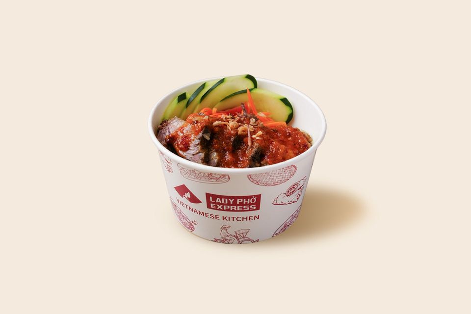 Cup of spicy red noodles topped with cucumber slices and sesame seeds