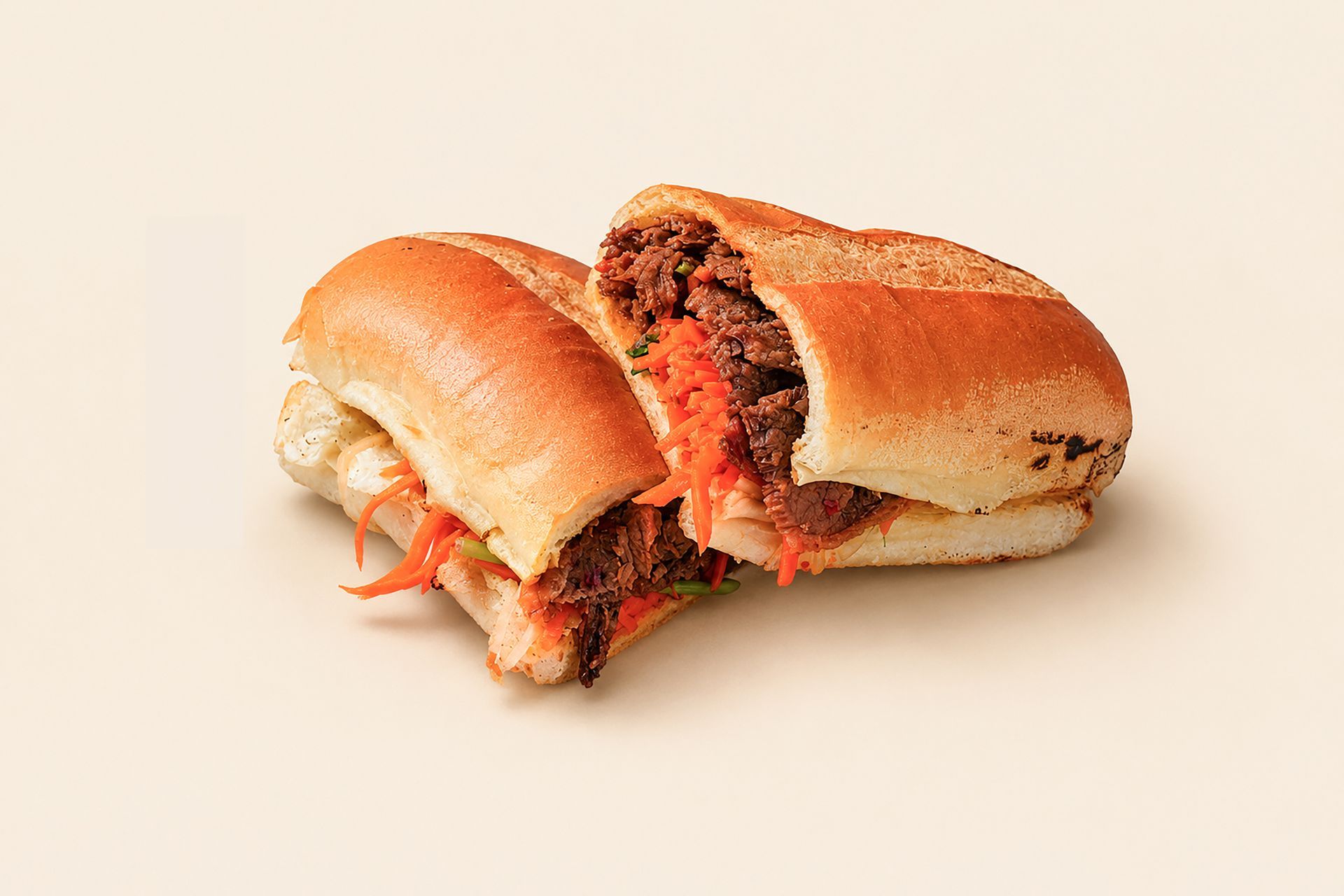Two halves of a sandwich with visible meat filling on a plain light background