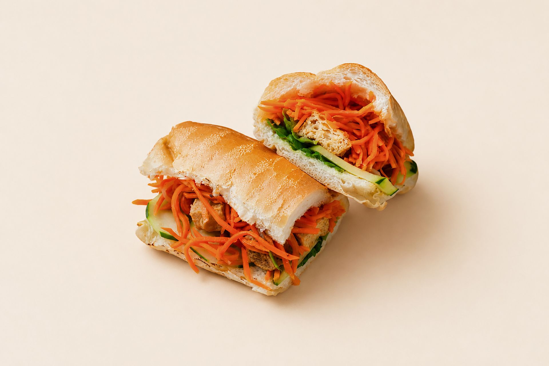 Two sandwich halves with shredded carrots and greens on a light beige background