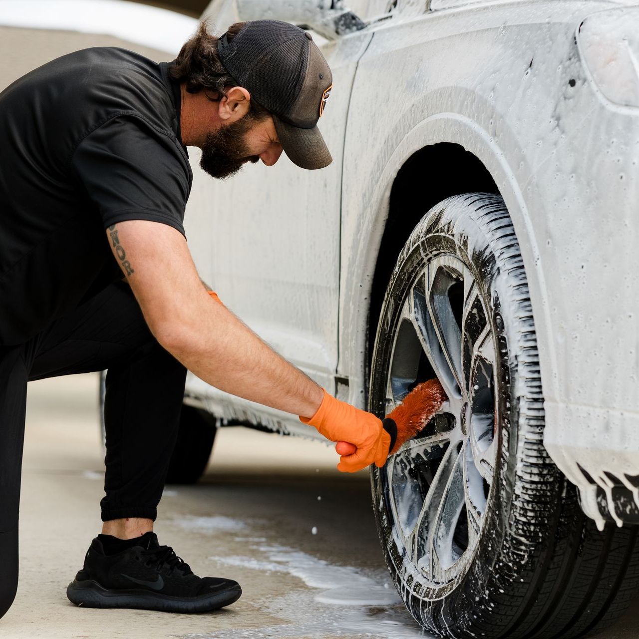 We provide top mobile exterior car detailing in Austin, TX. Man scrubbing tires with brush during monthly mobile car detailing in Dripping Springs, TX.