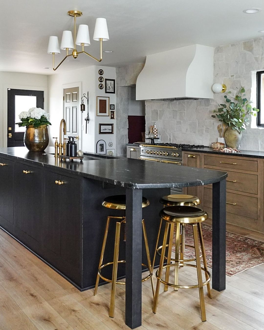 A kitchen with black cabinets and gold stools