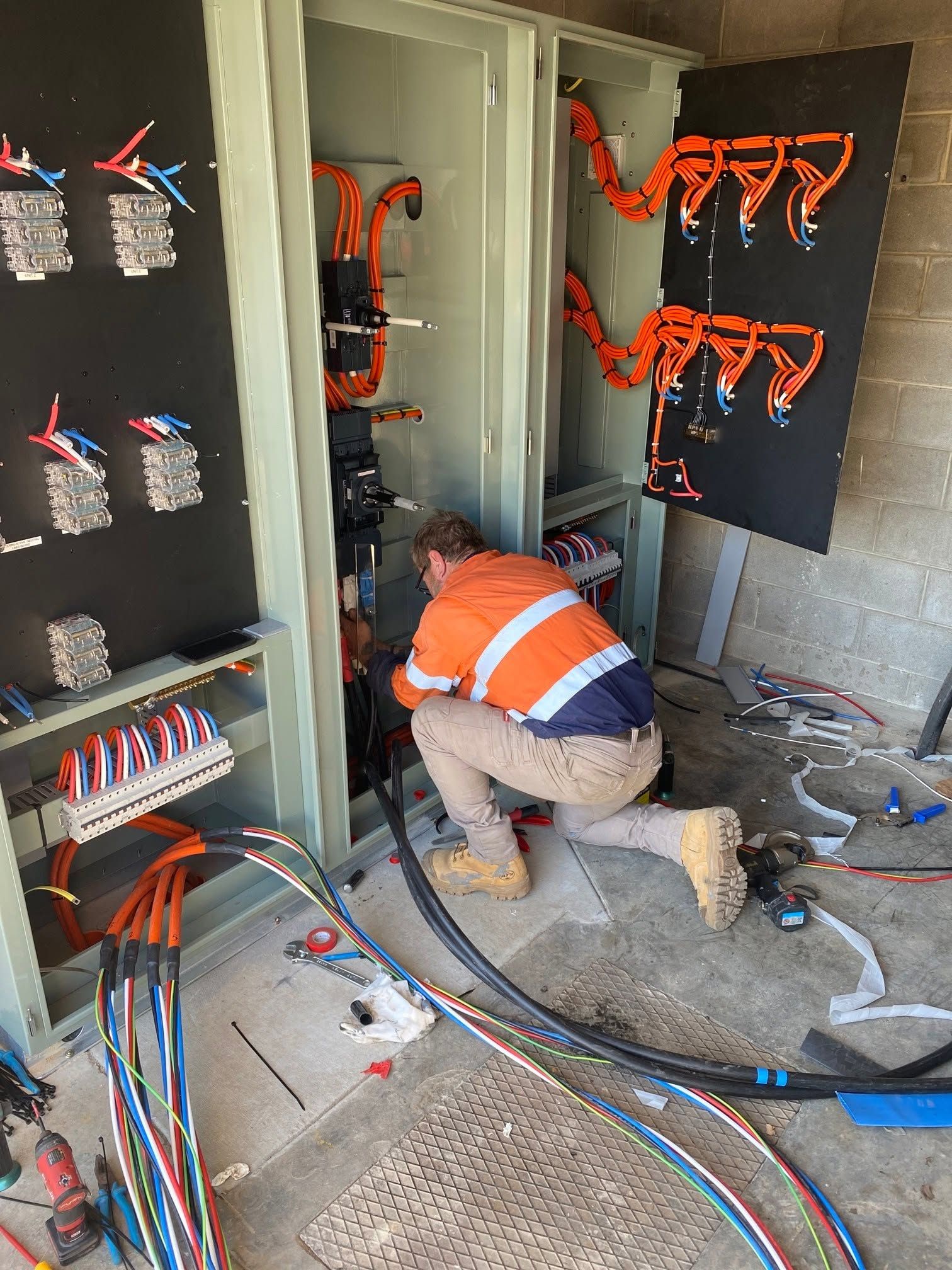 Worker Installing Electrical Wiring in An Open Cabinet — Premium Electrical Solutions In Coral Cove, QLD