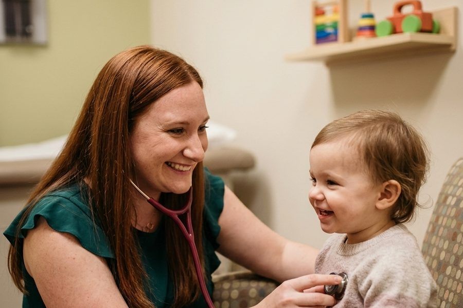 Dr. Wesp listening to a smiling toddler's heart with a stethoscope.