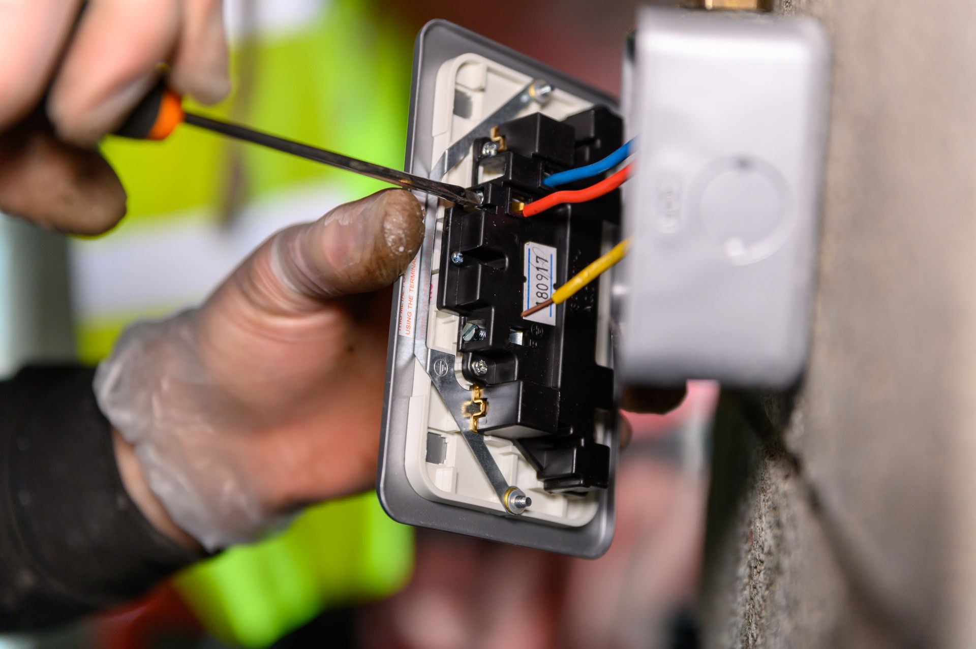 A man is kneeling on the floor working on an electrical outlet.