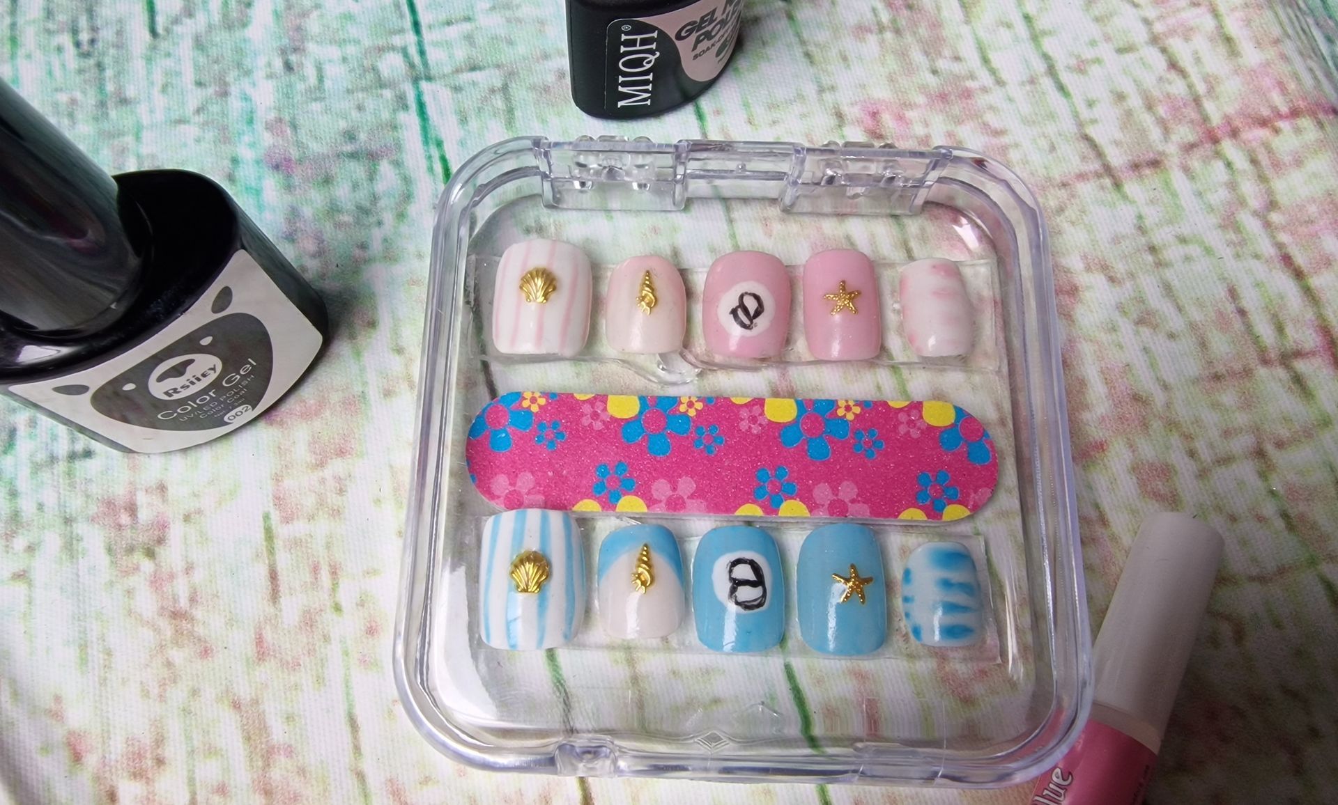 Schaal met kleurrijke plaknagels met bloemen- en patroonmotieven op een pastelkleurige ondergrond