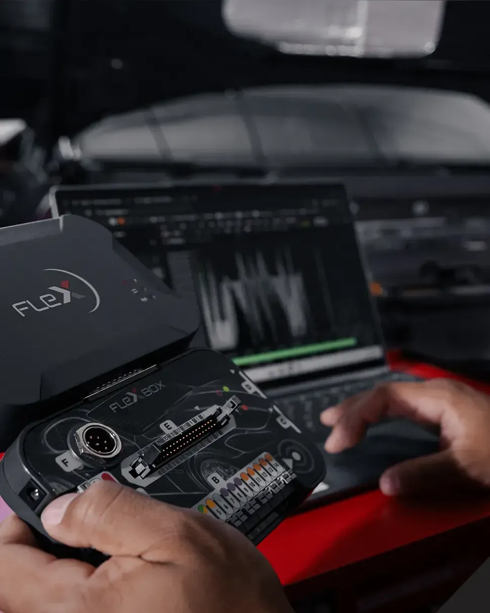 A laptop is sitting on a table next to a remapping device & ECU