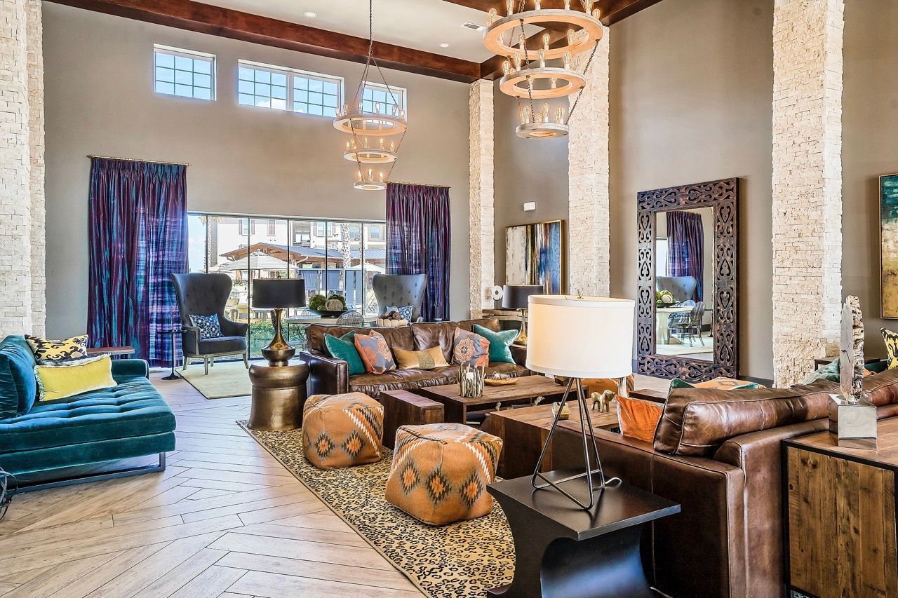 Spacious contemporary resident lounge with teal sofa, leather seating, and large windows.