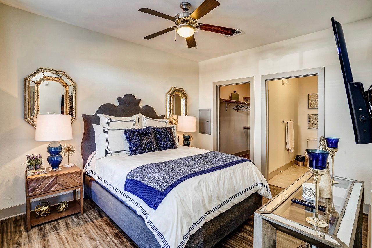 Bedroom with a large bed, two nightstands, lamps, and an open closet.