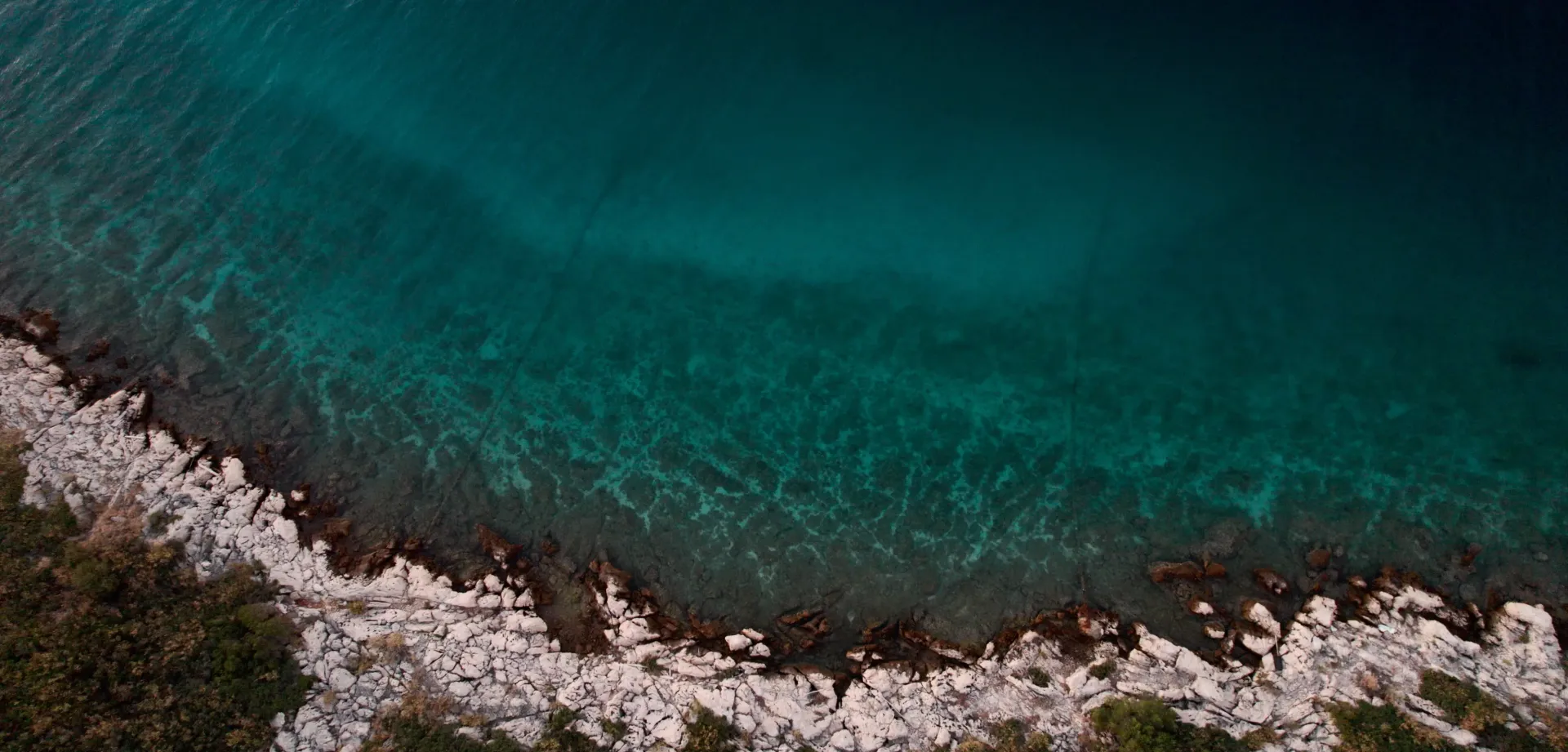 An aerial view of a large body of water surrounded by rocks and trees.