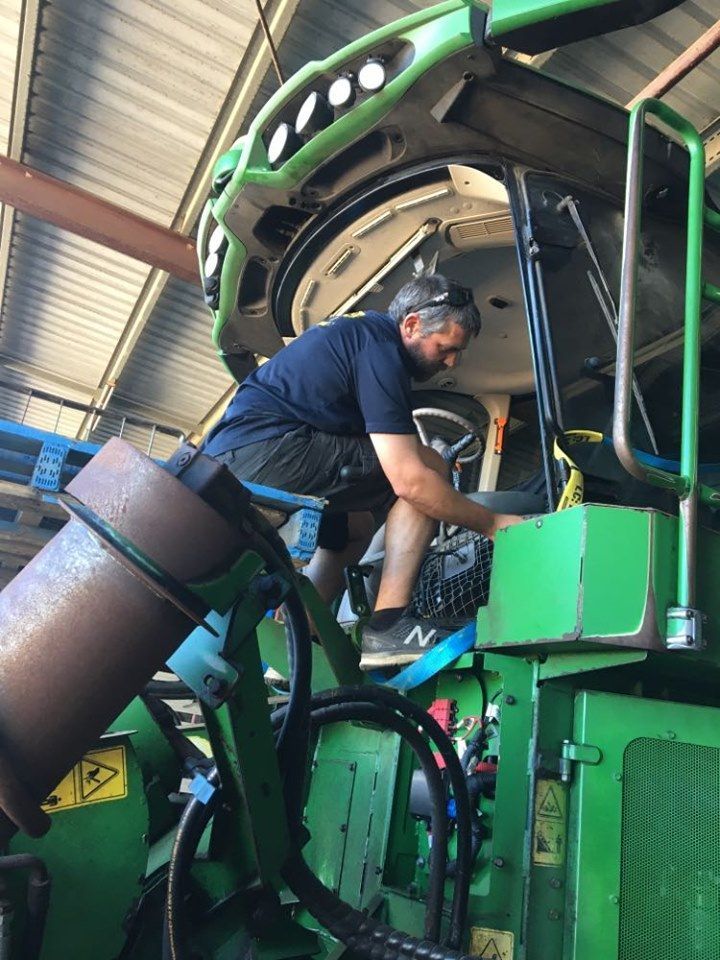 Man Working on Green Machinery in a Warehouse — Mobile Windscreens FNQ in Babinda, QLD