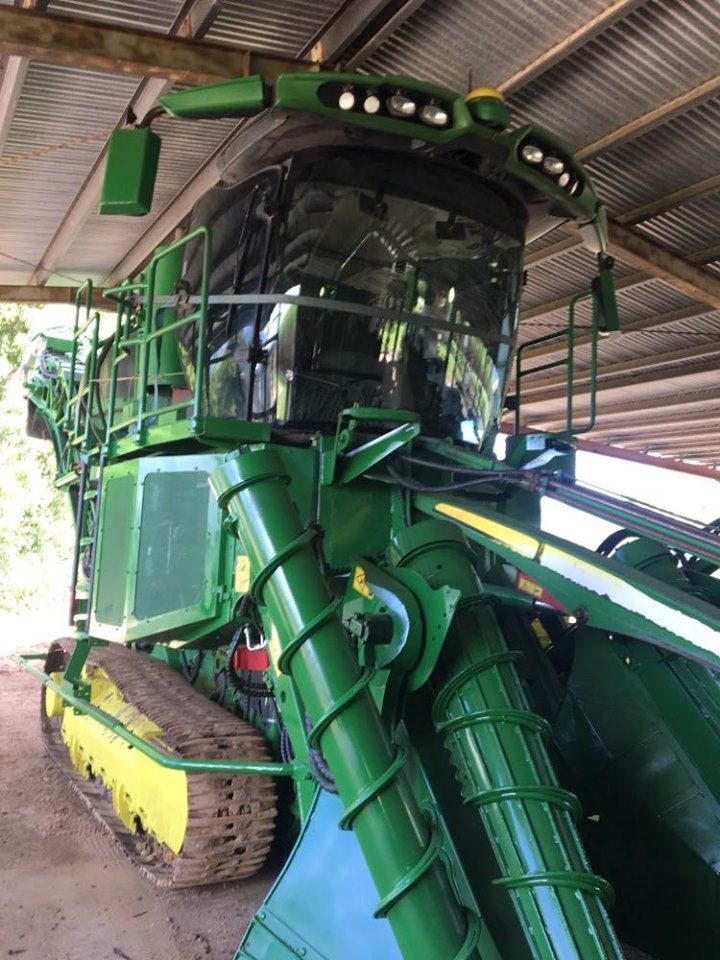 Green John Deere Sugarcane Harvester Under a Wooden Shed — Mobile Windscreens FNQ in Mareeba, QLD