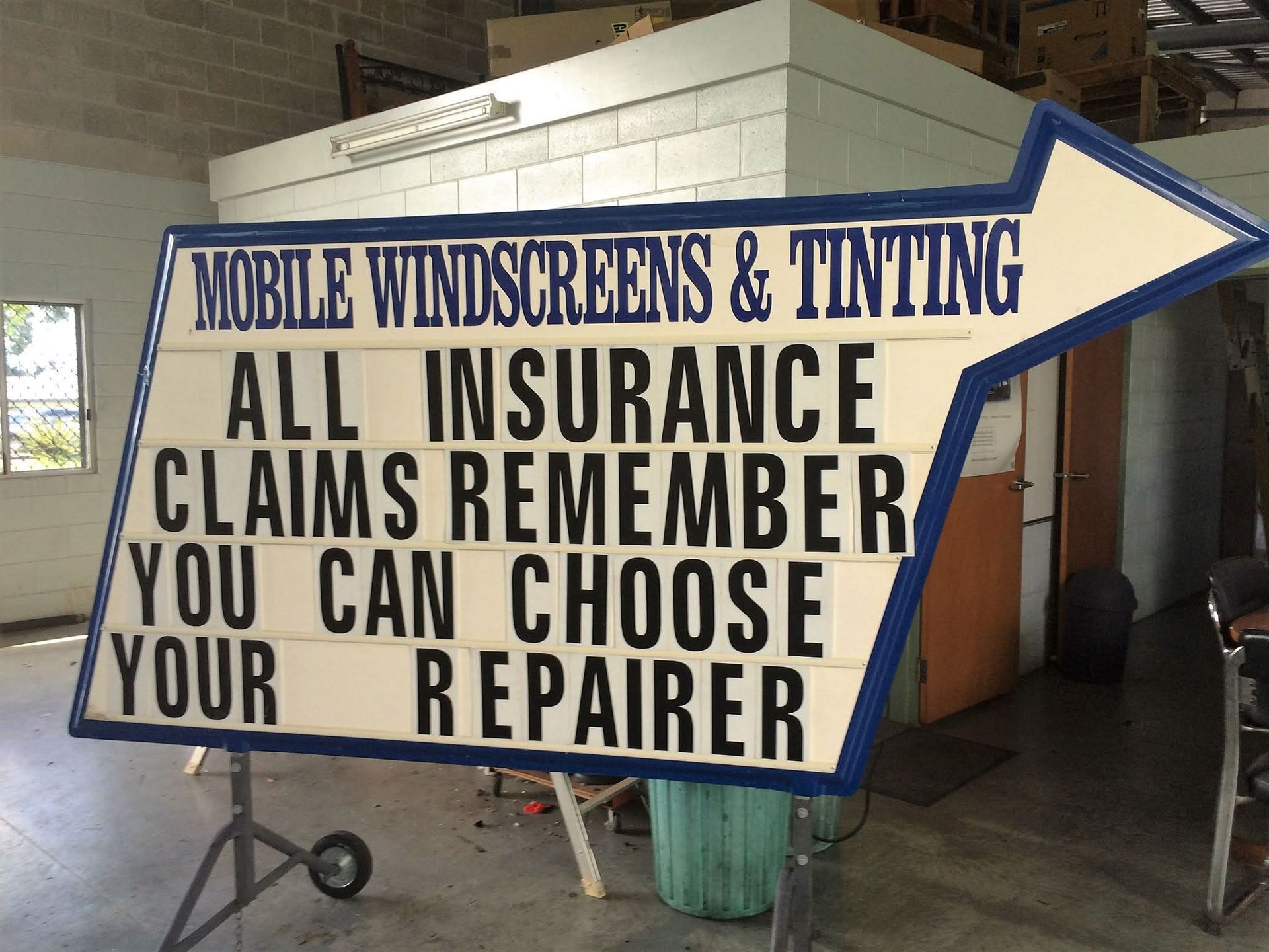 Blue and white roadside sign for mobile windscreens and tinting, advertising insurance claims and choosing your repairer