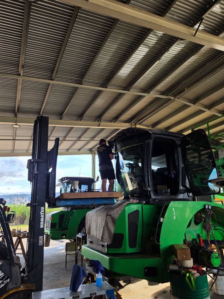 Green tractor parked under a shed, with a person working in the cab area.