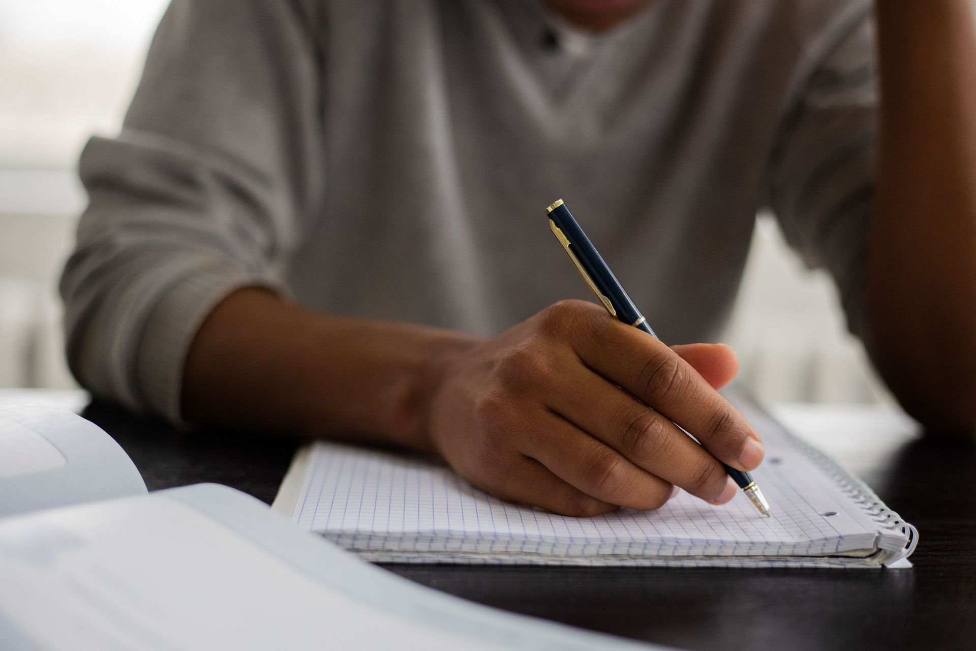 Person writing in a notebook at a desk, drafting a candidate statement for a condo or HOA board elec