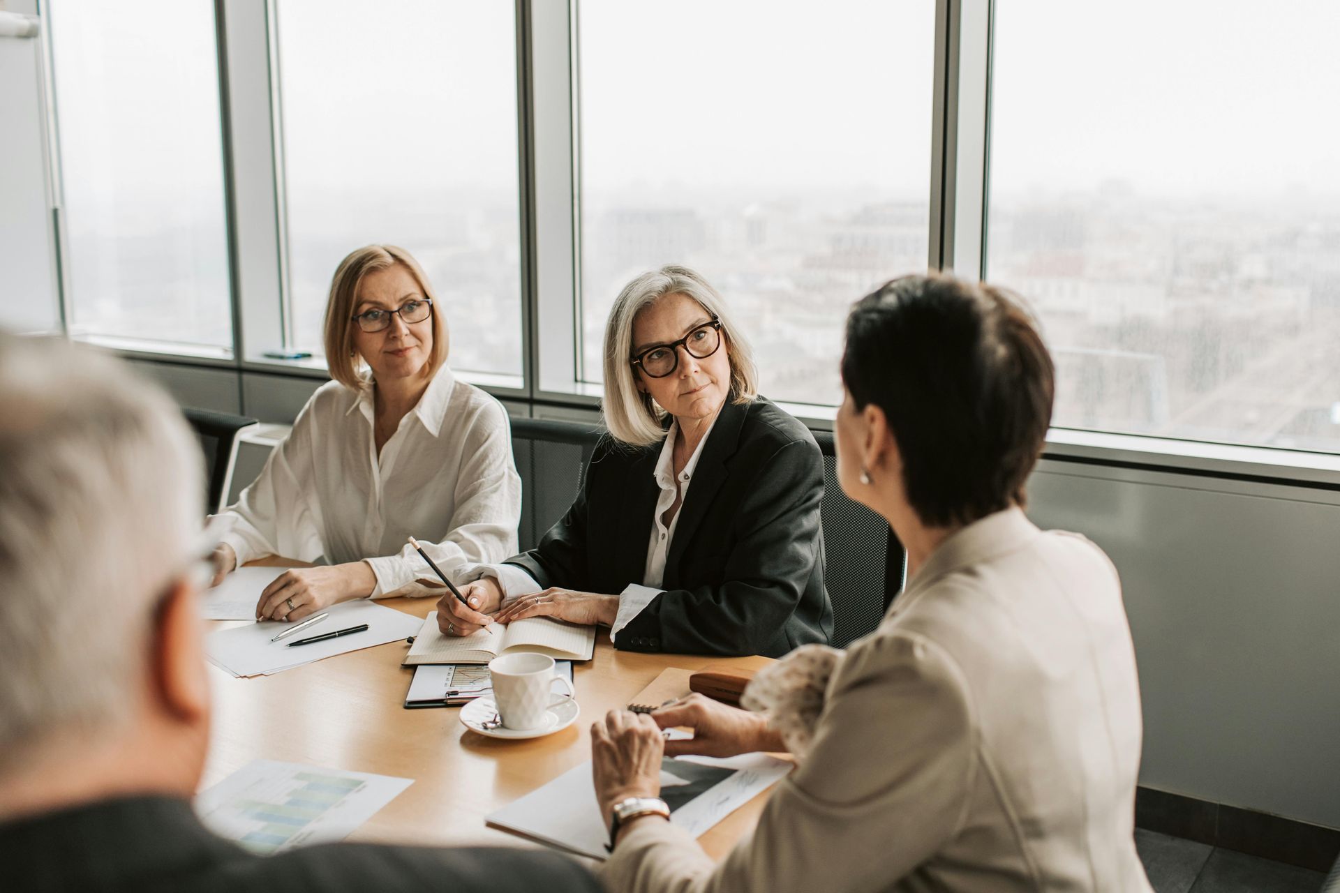 People in a meeting shaking hands around a conference table in a bright office