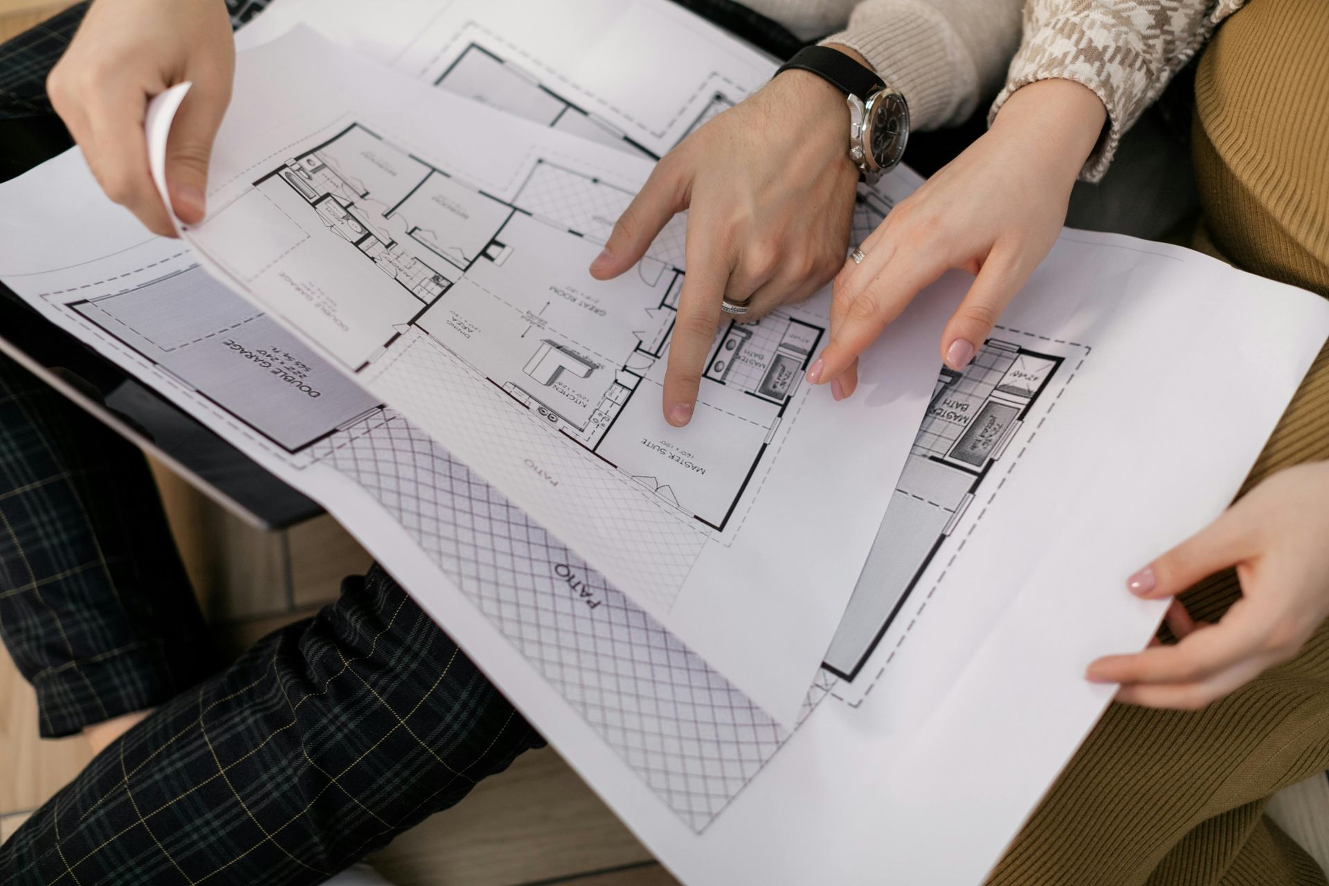 Three hands reviewing a printed floor plan on a table