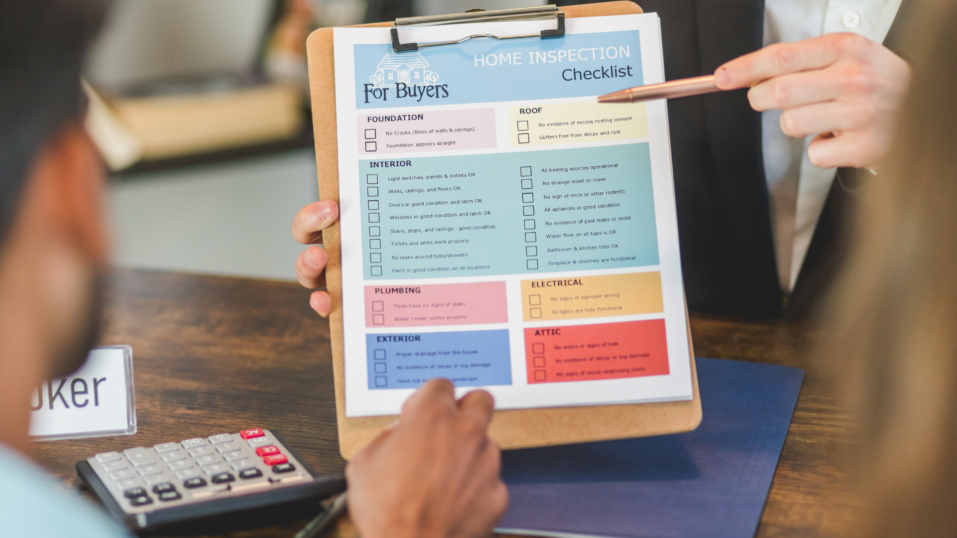 Person points to a colorful expense checklist on a clipboard beside a calculator on a desk
