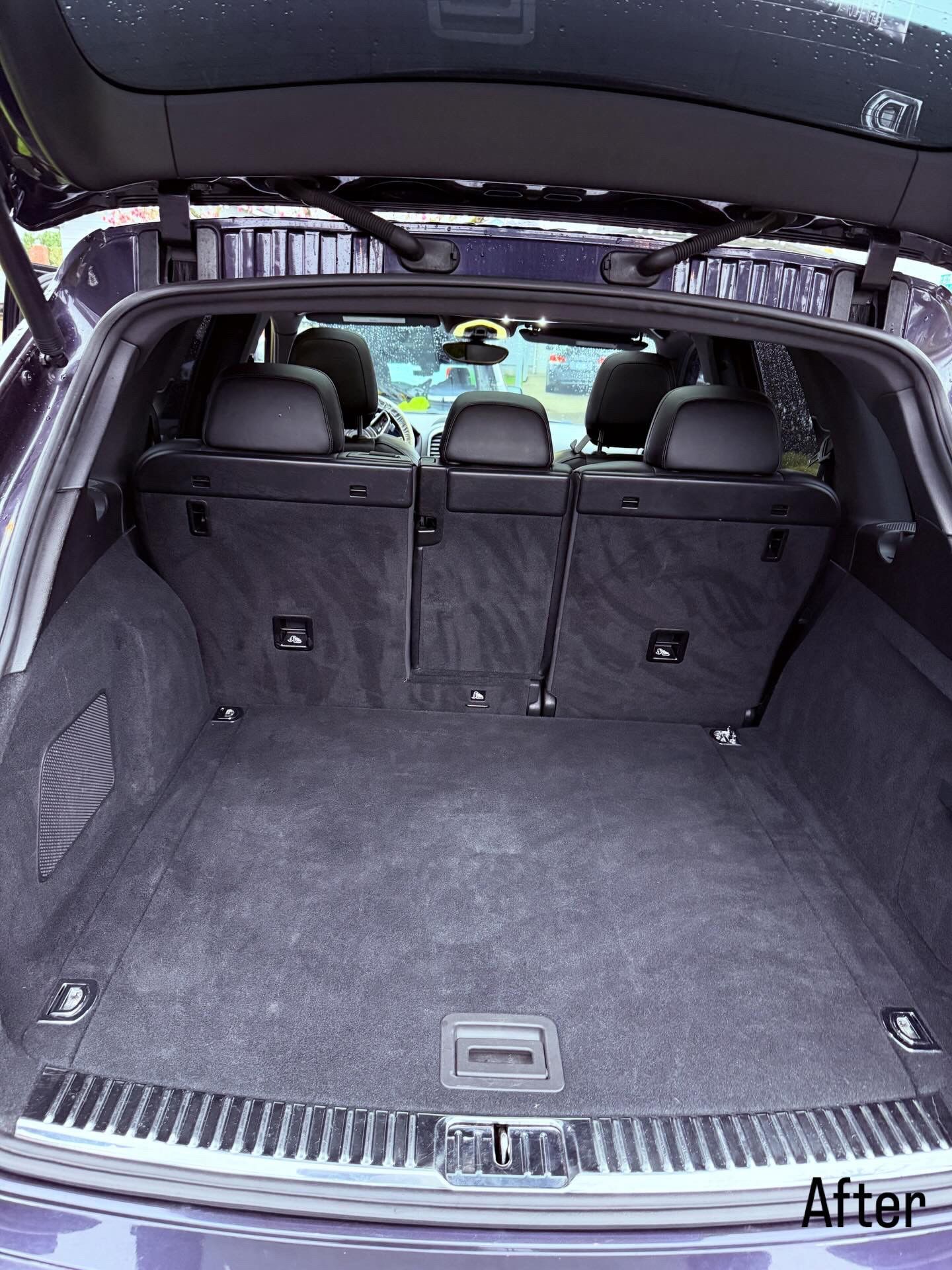 Empty car trunk with black carpeted cargo area and folded rear seats, viewed from the back