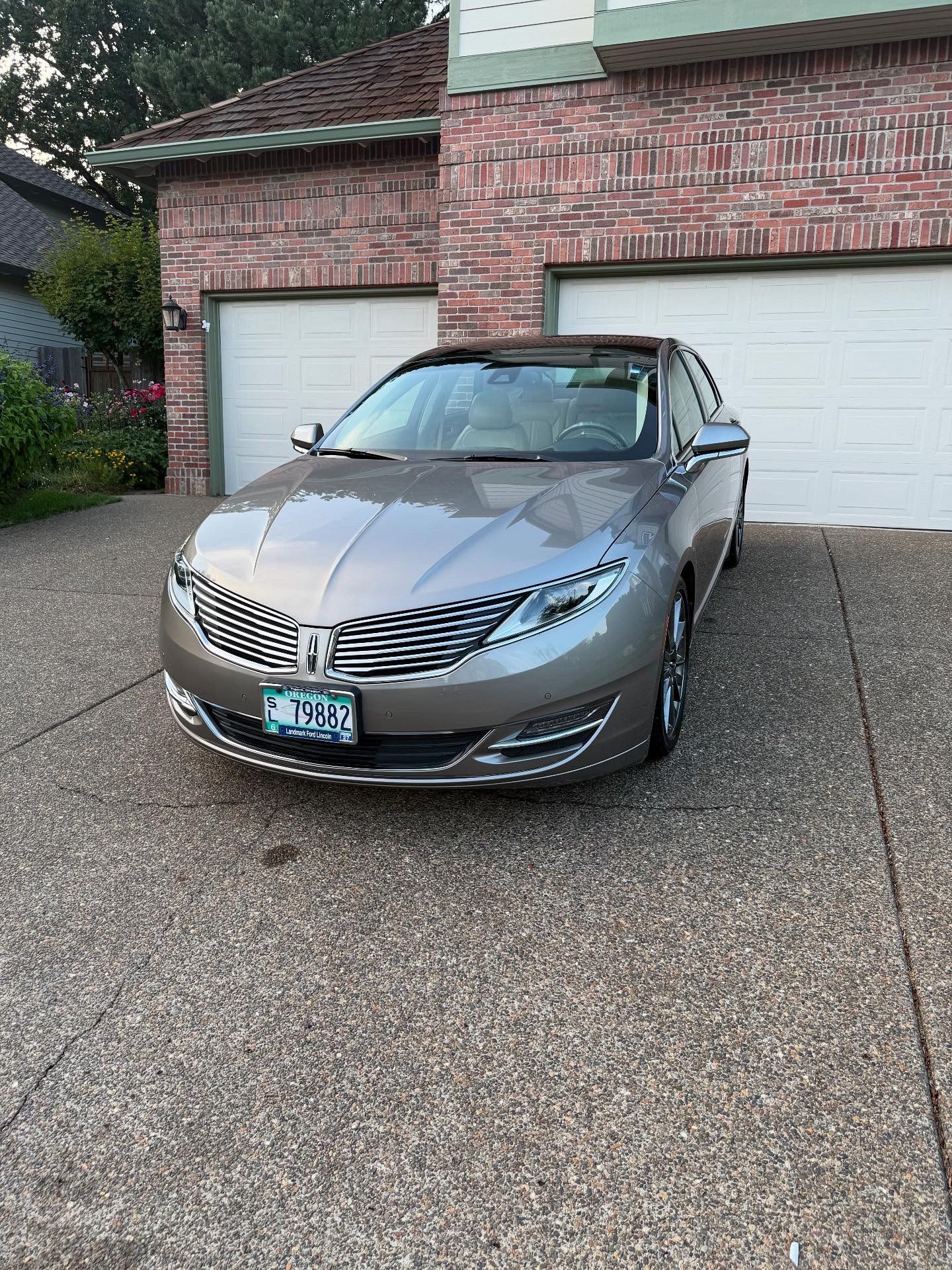 Silver sedan parked in a driveway in front of a brick garage
