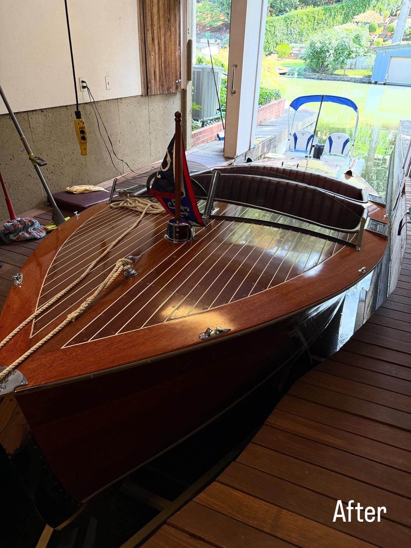 Wooden sailboat indoors, viewed from above, with red-and-blue rigging near open doors to a sunny patio