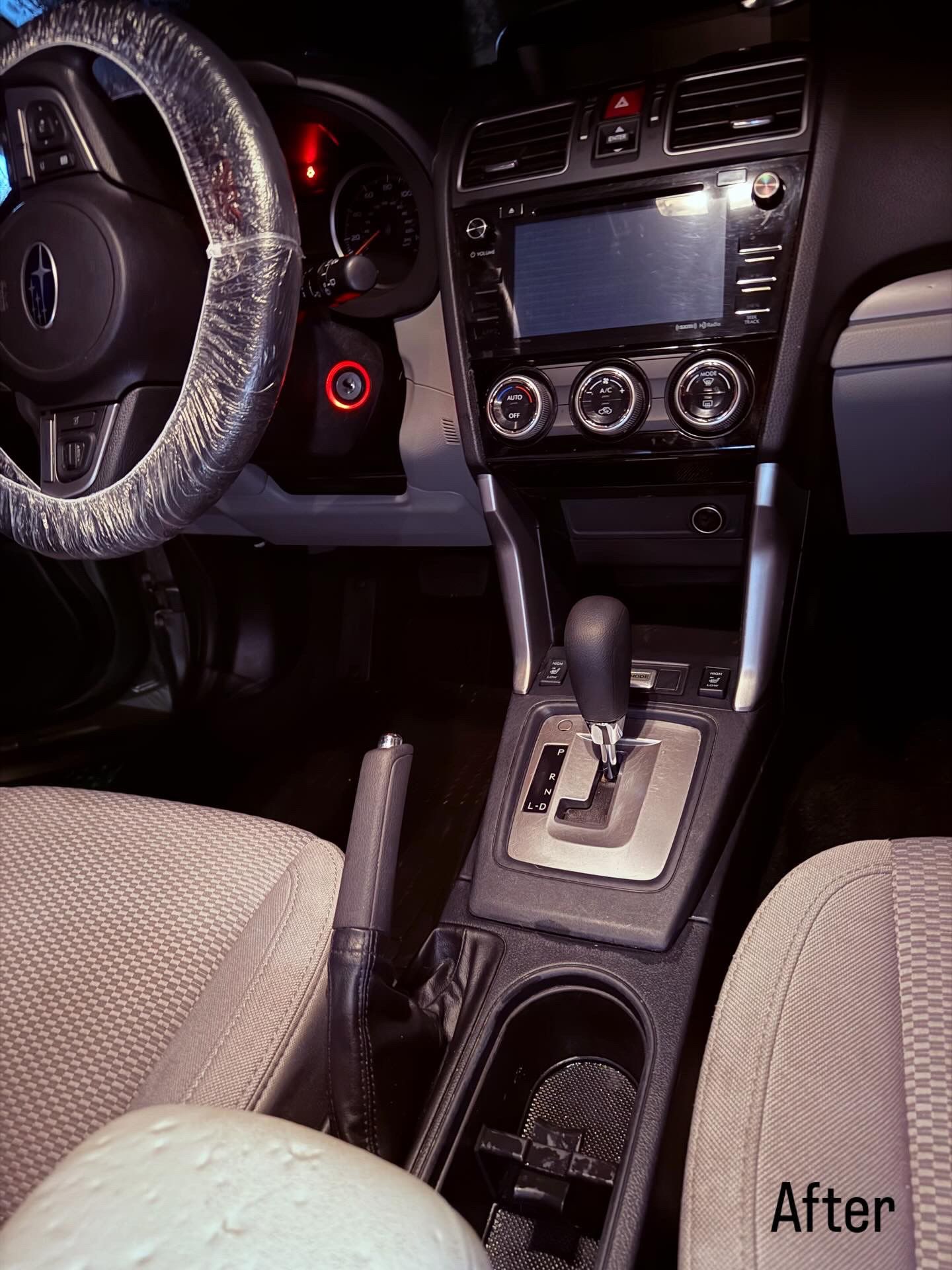 Car interior with the dashboard and center console lit up, showing the gear shift and radio controls.