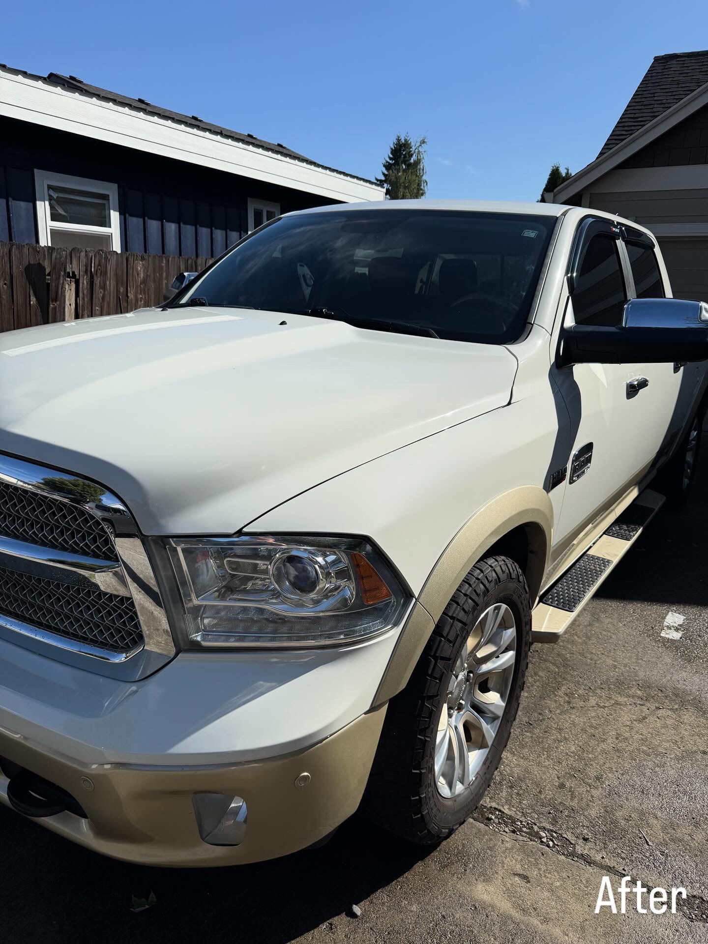 White pickup truck parked in a driveway beside a house, shown in bright sunlight.